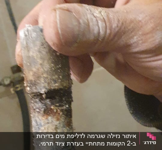 יד מחזיקה צינור חלוד עם נזילה